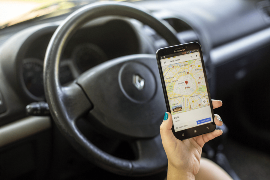 Photo of human hand holding a cell phone looking at a business location on their maps application. Contact bake more pies for help with optimizing your google my business listing!